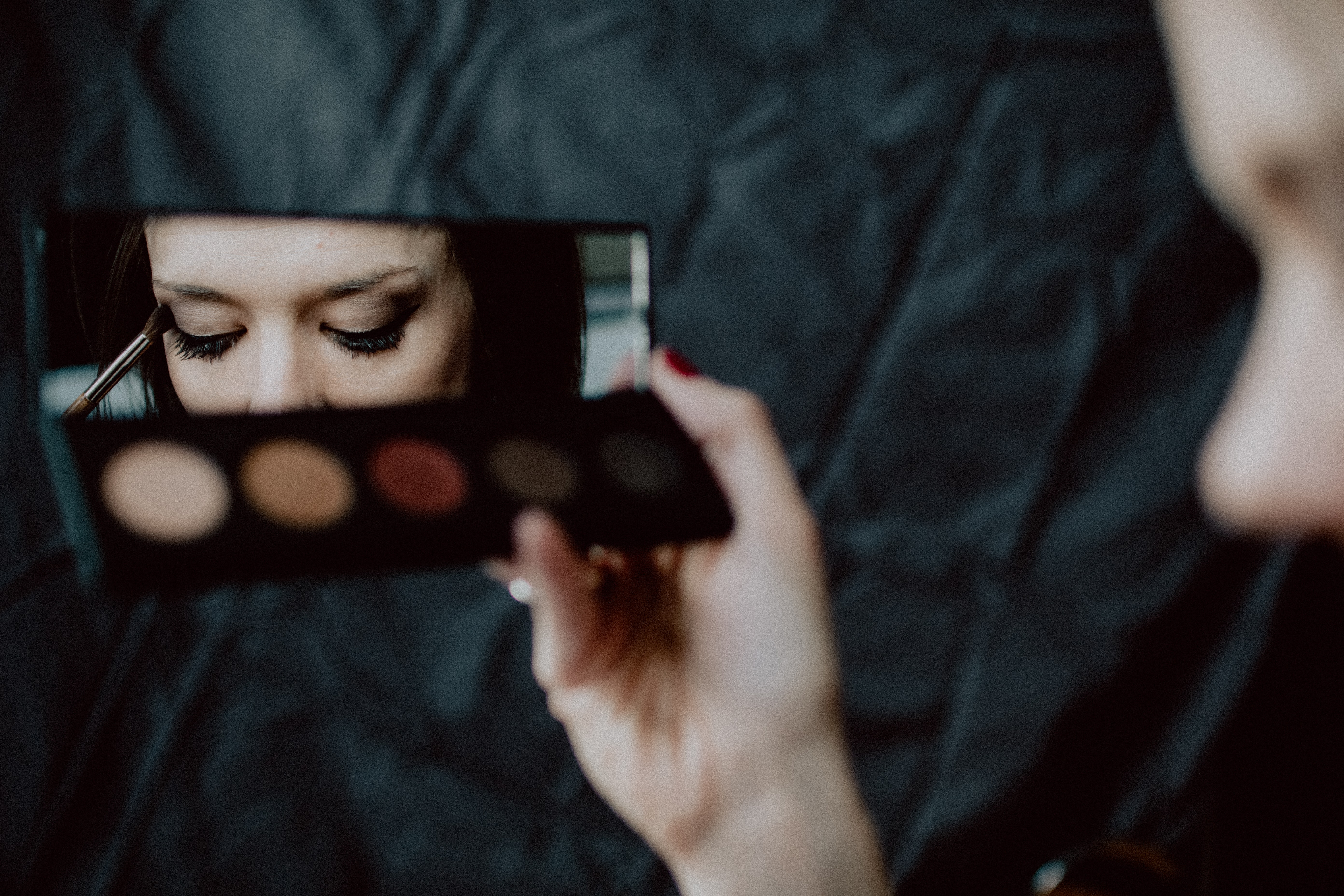 mujer sosteniendo paleta de maquillaje negro y plateado
